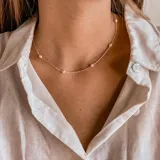 Gargantilla plateada con pequeñas perlas blancas espaciadas a lo largo de la cadena.