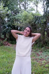 Chaleco tejido de punto en color crudo, con cuello alto y diseño sin mangas. Presenta una textura de punto grueso y corte recto.