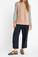 Chaleco de punto color beige con cuello alto y sisas amplias.