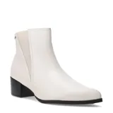 Bota tipo Chelsea de cuero color marfil, con paneles elásticos laterales, puntera redondeada y taco cuadrado bajo de color negro.