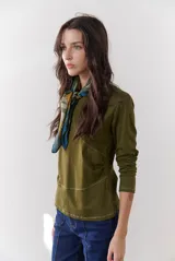 Remera blanca de manga larga con cuello redondo y costuras decorativas en contraste de color negro.