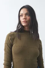 Polera de tejido de punto color celeste, con cuello alto y textura de pequeños puntos en relieve formando una cuadrícula en el frente y las mangas. De corte ajustado y manga larga.