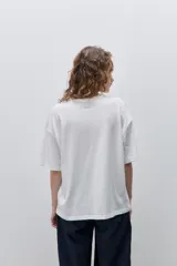 Remera negra de silueta amplia y calce relajado, con cuello redondo, mangas cortas con hombros caídos y estampa botánica en líneas blancas en el frente.