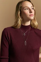 Polera de tejido acanalado color bordó, con cuello alto y diseño geométrico en relieve que estiliza la figura. Presenta un ajuste al cuerpo y mangas largas.