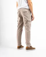 Pantalón cargo negro de corte slim, confeccionado principalmente en algodón con un pequeño porcentaje de spandex para elasticidad. Presenta múltiples bolsillos utilitarios con tapa y remaches de refuerzo.