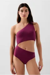 Bañador enterizo de color violeta con diseño asimétrico de un solo hombro y abertura cut out en la cintura. Cuenta con copas extraíbles y forro interior completo.
