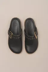 Zueco destalonado de cuero vacuno con estampado de leopardo. Presenta una tira ancha con hebilla metálica dorada sobre el empeine.