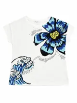 Remera blanca de manga corta, con cuello redondo y diseño estampado que combina una gran flor azul en el hombro derecho con una ola de estilo japonés en la parte inferior izquierda, conectadas por puntos negros.