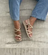 Sandalias planas color beige con tiras cruzadas y tachas doradas.