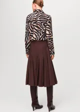 Camisa de poliéster con estampado de animal print estilo cebra en tonos negro, beige y marrón, de manga larga y cuello clásico con cierre frontal de botones.