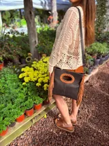 Cartera bandolera negra de cuero con forro interno de tela, detalle de flecos de cuero marrón en la parte inferior y asa larga regulable.