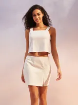 Musculosa corta de color blanco, confeccionada con mezcla de lino, con escote cuadrado y tirantes anchos.