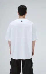 Remera de corte oversize color blanco, con cuello redondo y mangas cortas amplias. Presenta una costura horizontal decorativa en la parte media delantera.