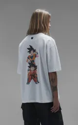 Remera blanca de corte oversize con cuello redondo y mangas cortas. Presenta un estampado central en la espalda con los personajes Goku y Goten de Dragon Ball.