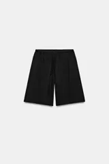 Bermuda de algodón color negro, con tiro medio, cintura elástica ajustable con cordones y bolsillos laterales ocultos en costura.