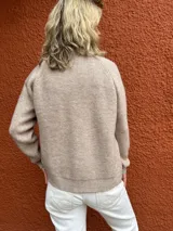 Campera de tejido de punto en color beige melange, con cierre frontal completo, cuello alto y mangas largas con puños acanalados.