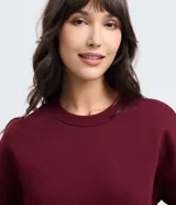 Buzo femenino de cuello redondo y manga larga, confeccionado en tejido de algodón con felpa. Presenta un diseño básico sin estampado, con puños y ruedo ajustados en tejido rib.