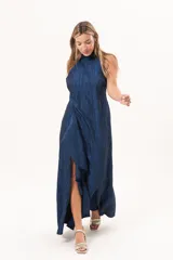 Vestido largo azul de tafeta con textura corrugada, cuello halter, espalda descubierta y falda amplia con tajo lateral y volados.