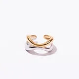 Anillo abierto ajustable con diseño de dos bandas cruzadas, una en tono dorado y otra en tono plateado.