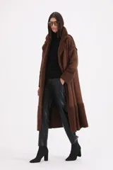Tapado largo de gamuza color chocolate con detalles de corderito en solapas, puños y ruedo. Presenta cierre frontal con botones y corte recto.