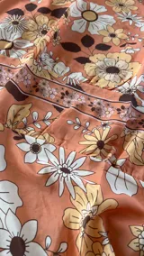 Vestido largo naranja con estampado floral de estilo setentero, escote en V profundo y tirantes finos.