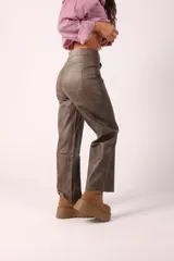 Pantalón de corte recto y holgado confeccionado en eco cuero con acabado texturizado. Presenta diseño de cinco bolsillos, cierre frontal y costuras reforzadas en los laterales.