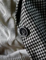 Blazer con estampado de pata de gallo en blanco y negro, marca Tahari. Tiene cuello con solapa, abertura central con botones, bolsillos delanteros y forro a tono.