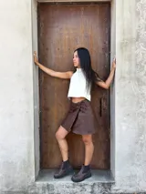 Minifalda tipo pareo confeccionada en cuero color chocolate, con diseño cruzado y cierre mediante tiritas laterales ajustables.