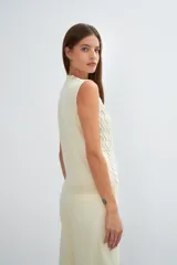 Chaleco de lana color crudo, tejido con escote en V y diseño con diferentes puntos combinados en el frente.