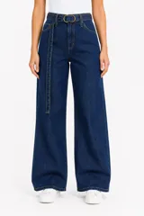 Pantalón jean azul de tiro alto y corte ancho, con presillas, bolsillos y cinturón incorporado del mismo género con hebilla metálica circular.