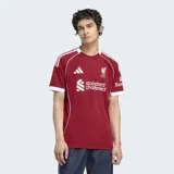 Camiseta de fútbol Adidas del Liverpool FC, modelo Home temporada 25/26, para hombre. Diseño color rojo oscuro con ribetes y detalles en blanco en cuello, mangas y hombros. Incluye el escudo del club y logos de patrocinadores.