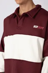 Buzo tipo polo de calce relajado con diseño de bloques de color en tonos marrón y blanco. Presenta cuello polo, cierre frontal parcial y logo estampado en el pecho. Confeccionado en tejido pesado con estructura.