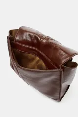 Bolso tipo mini shopper confeccionado en piel con acabado brillante. Presenta un diseño de doble compartimento con cierre de botón imantado y asa de hombro ajustable.