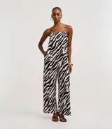 Mono largo de sastrería marca Cortelle, confeccionado en crepé con elastano, con estampado animal print de cebra en tonos beige y negro. Presenta escote recto, tirantes finos regulables, corte wide leg en las piernas y un cinturón ancho ajustable en la cintura.