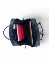 Bolso de mano tipo maletín, confeccionado en cuero natural y gamuza negra con bordado decorativo en tono azul. Cuenta con doble asa superior, cierre principal con doble cursor y base con topes metálicos.