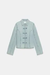 Camisa de denim celeste con cuello solapa, manga larga y cierre frontal con nudos de tela.