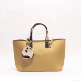 Cartera tipo tote de cuero sintético color amarillo, con doble asa de mano con estampado de vaca en blanco y marrón, y un monedero colgante a juego.