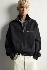 Sudadera de corte relajado confeccionada en denim de algodón con efecto lavado. Presenta cuello subido con cierre frontal de cremallera, manga larga con puños elásticos y bajo elástico. Incluye un bolsillo con cierre de cremallera en el pecho.
