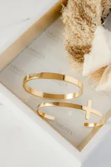 Brazalete abierto dorado de acero quirúrgico con dije de cruz.