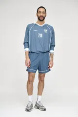 Camiseta de fútbol celeste con rayas verticales, cuello polo y mangas 3/4 con puños blancos. Incluye el número 78 en el frente y logos estampados.