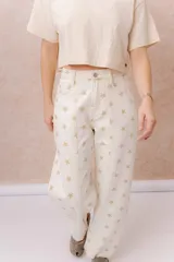 Jean de tiro alto confeccionado en denim color crudo, con estampa de estrellas en tono camel. Presenta calce relajado, pierna recta levemente amplia, costuras verticales delanteras, cinco bolsillos, pasacintos y detalle metálico en la parte posterior.