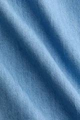 Vestido midi de denim suave, color azul claro, con escote cuadrado, espalda escotada y tirantes anchos. Presenta un cuerpo ajustado y una falda acampanada con frunces en las caderas que aportan volumen.