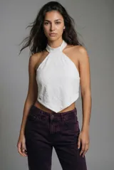 Top blanco con cuello halter y diseño en punta tipo pañuelo. Confeccionado en tejido con textura, sin mangas y con espalda descubierta.