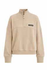 Sweater de tejido acanalado color beige, con cuello alto y cierre frontal parcial tipo medio cierre. Presenta mangas largas con puños anchos y un pequeño parche rectangular con el logo de la marca en el pecho.