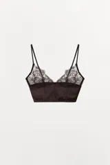 Bralette de diseño combinado en tejido satinado y encaje, con escote en pico y tirantes finos ajustables. Presenta bordados florales a tono y cierre posterior con ganchos metálicos.