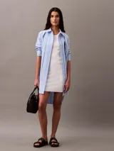 Vestido corto ajustado de punto canalé, con cuello redondo y diseño sin mangas. Presenta un corte bodycon que se adapta a la silueta.