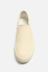 Zapatilla slip-on negra de tejido de algodón con elásticos laterales y suela color crema.