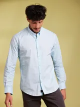 Camisa de manga larga en color celeste, con cuello abotonado y corte slim fit. Presenta cierre frontal con botones y logo bordado sutil en el pecho.