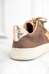 Zapatillas bajas de cuero color marrón con estrella beige en el lateral, cordones color beige y detalle dorado en el talón.