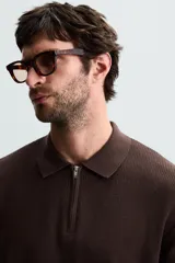 Polo de manga corta, color azul medio, tejido en punto perlado con cuello solapa y cierre frontal de cremallera.